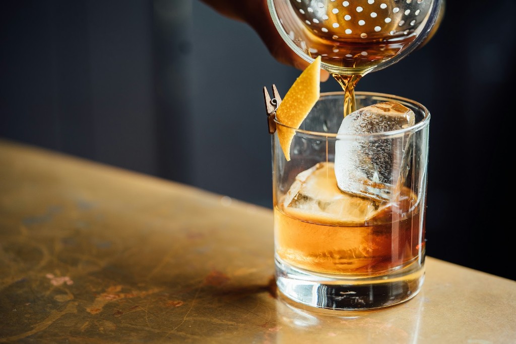 A cocktail being poured over ice