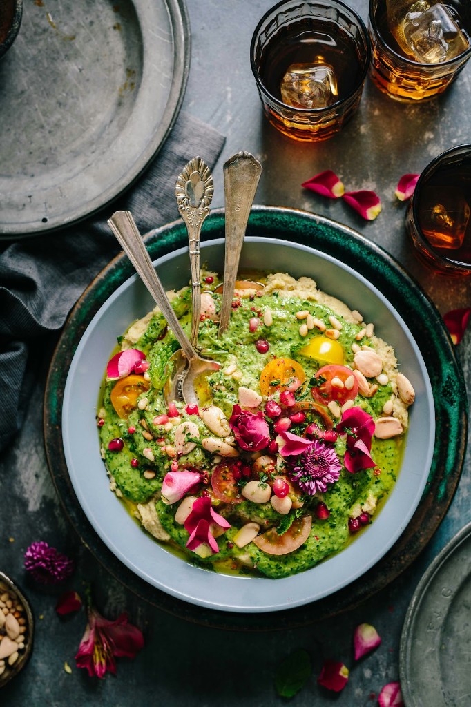 A colorful vegan dish with herbs, nuts, and flowers